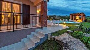 Una casa moderna con patio, mobiliario exterior y piscina.