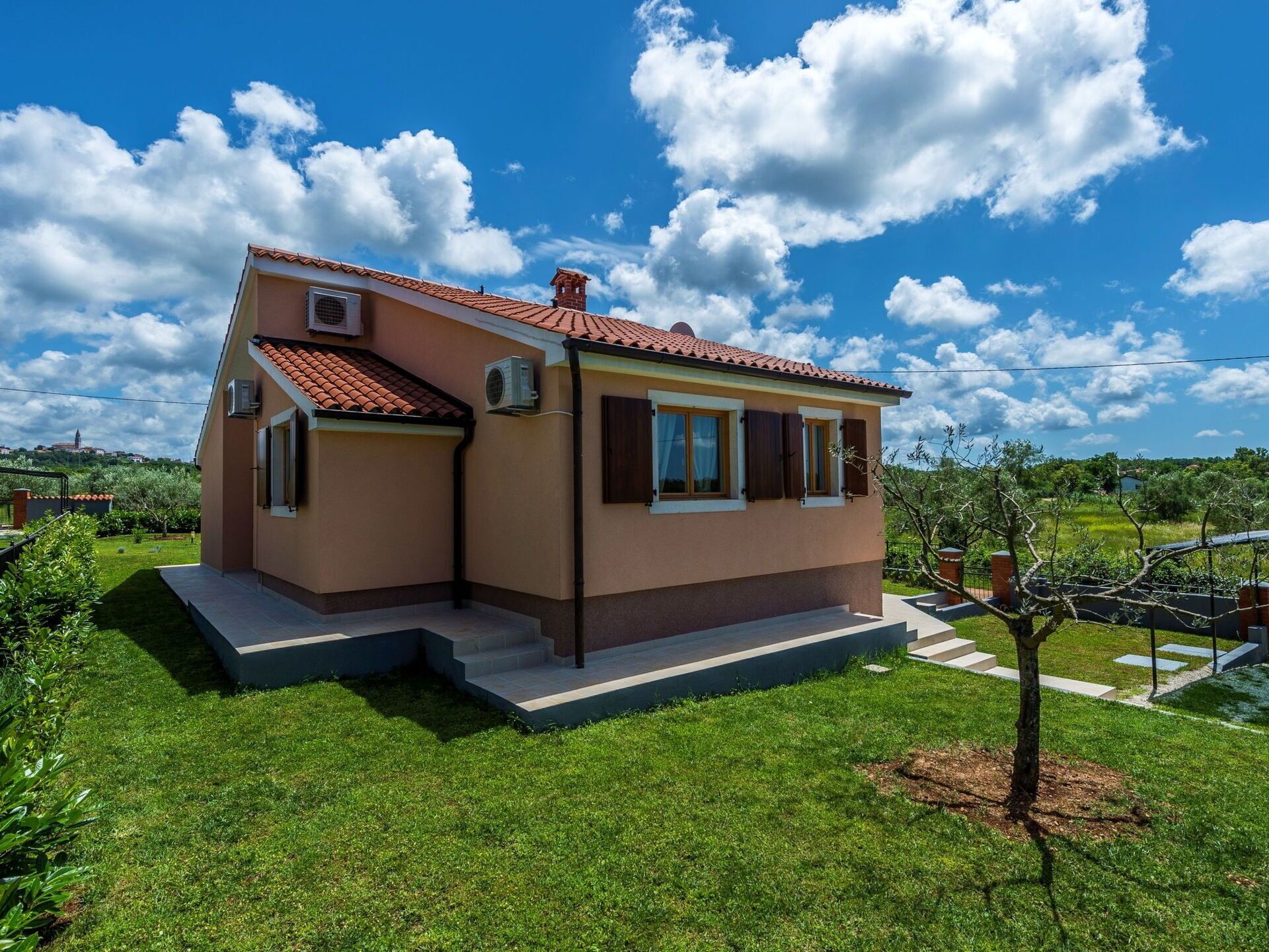 A single-story house with a red-tiled roof, a small front porch, and a well-maintained lawn.