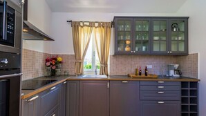 Una cocina moderna con armarios grises, horno empotrado y cafetera.