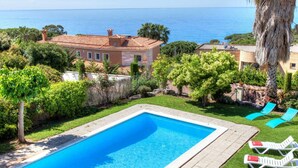 Une piscine rectangulaire à l’eau d’un bleu cristallin, entourée d’une pelouse bien entretenue et de quelques chaises longues.