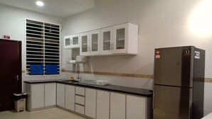 A kitchen with white cabinets, a black refrigerator, and a window with blinds. - BB Villas - 5 min Jonker Melaka (Malacca City)