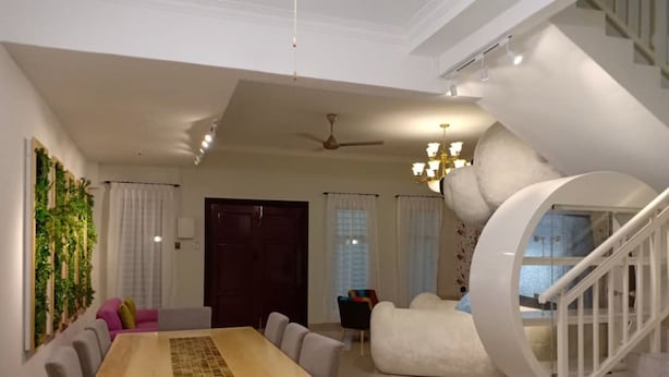 A modern living room with a wooden dining table, a sofa, and a spiral staircase. - BB Villas - 5 min Jonker Melaka (Malacca City)