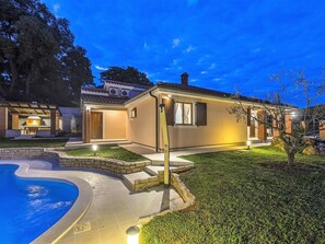 Una propiedad residencial con piscina, zona de barbacoa y patio bien iluminado.