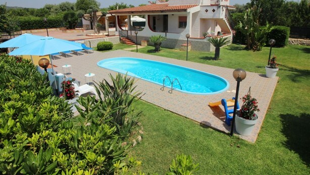 Ein Swimmingpool mit Sonnenschirm, Liegestühlen und einer kleinen Liegefläche.