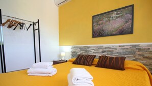Ein Hotelzimmer mit Bett, Handtüchern, einem Gemälde und einem Wandheizgerät.