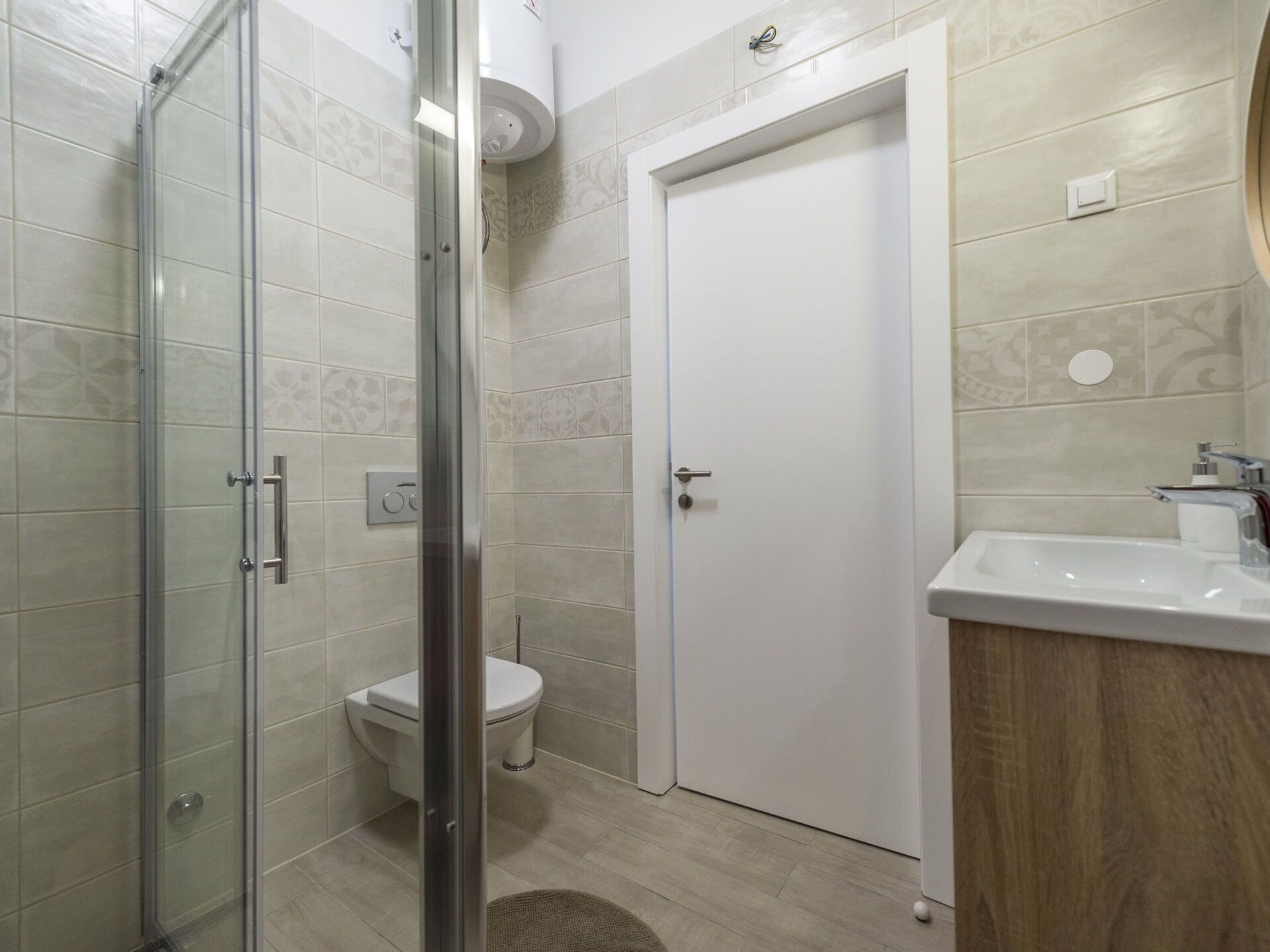 A bathroom with a glass shower enclosure, a toilet, and a sink with a mirror.