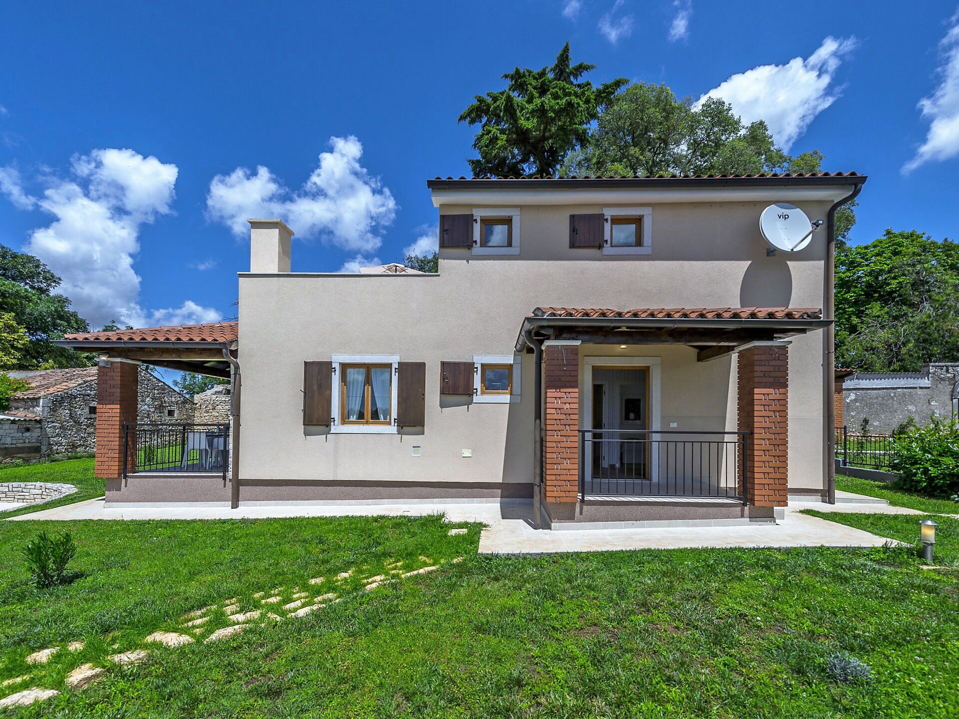 A two-story house with a satellite dish, a balcony, and a small garden area.
