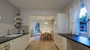 Una cocina moderna con armarios blancos, encimera negra y un comedor con mesa y sillas.