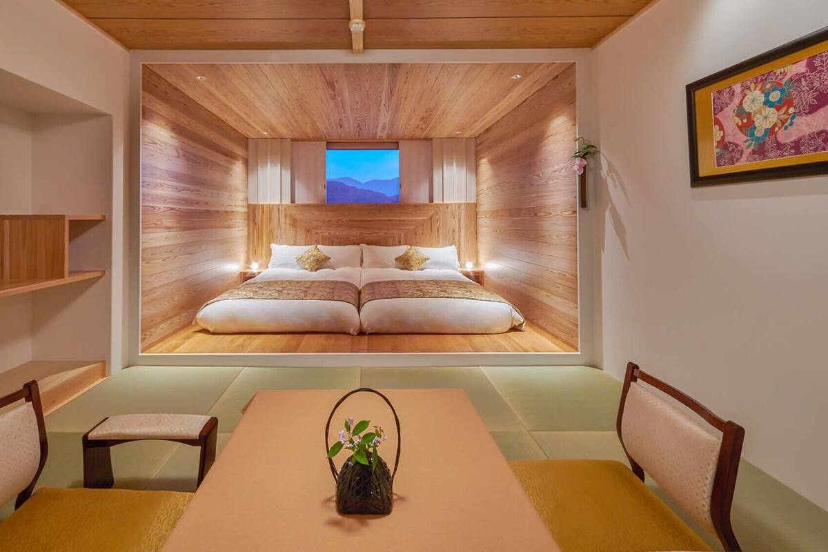A room with a bed, a dining table, chairs, and a small stool.