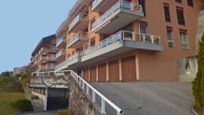 Ein mehrstöckiges Wohngebäude mit Balkonen, einer Garageneinfahrt und einem Parkplatz.