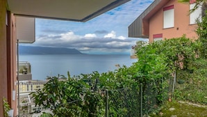 Ein Balkon mit Blick auf das Meer und ein Gebäude mit roter Fassade.