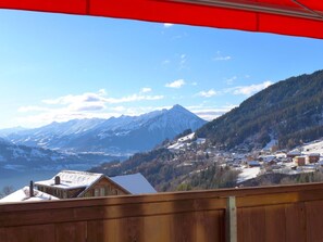 Une ville de montagne aux bâtiments couverts de neige, offrant une vue dégagée sur les montagnes enneigées qui se dressent à l’horizon.
