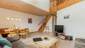A modern living room with a dining area, a staircase, and a television. - Beautiful apartment for 4 guests with WIFI, TV, balcony and panoramic view (Mauren)