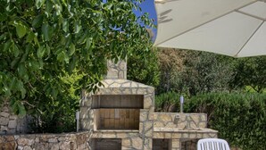 An outdoor stone barbecue area with two white chairs and an umbrella. - Wonderful private villa for 10 guests with private pool, WIFI, A/C, TV, terrace and pets allowed (Koromacno)