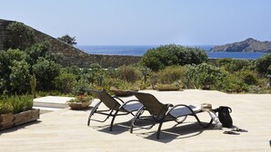 Un patio con muebles de exterior, un muro de piedra y vistas al mar.