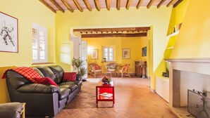 A living room with a black leather sofa, a red coffee table, and a fireplace. - Beautiful private villa for 10 guests with private pool, WIFI, A/C, TV, patio and pets allowed (San Vincenzo)