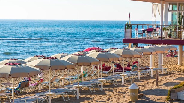 A beach with rows of sun umbrellas and lounge chairs, a lifeguard tower, and the ocean in the background. - Beautiful private villa for 10 guests with private pool, WIFI, A/C, TV, patio and pets allowed (San Vincenzo)