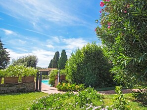 Un jardin avec un mur de pierre, une piscine et une pergola.