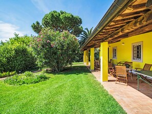 Un bâtiment jaune doté d’un patio, d’un espace extérieur aménagé pour s’asseoir et d’un jardin bien entretenu.
