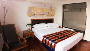 A hotel room with a bed, a chair, a nightstand, a lamp, a wall-mounted air conditioner, and a large window. - Beijing Perfect Inn Hotel (Beijing)