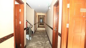 A hotel hallway with wooden doors, a carpeted floor, and a staircase. - Beijing Perfect Inn Hotel (Beijing)