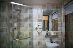 Un baño con cabina de ducha de vidrio, lavabo y espejo.