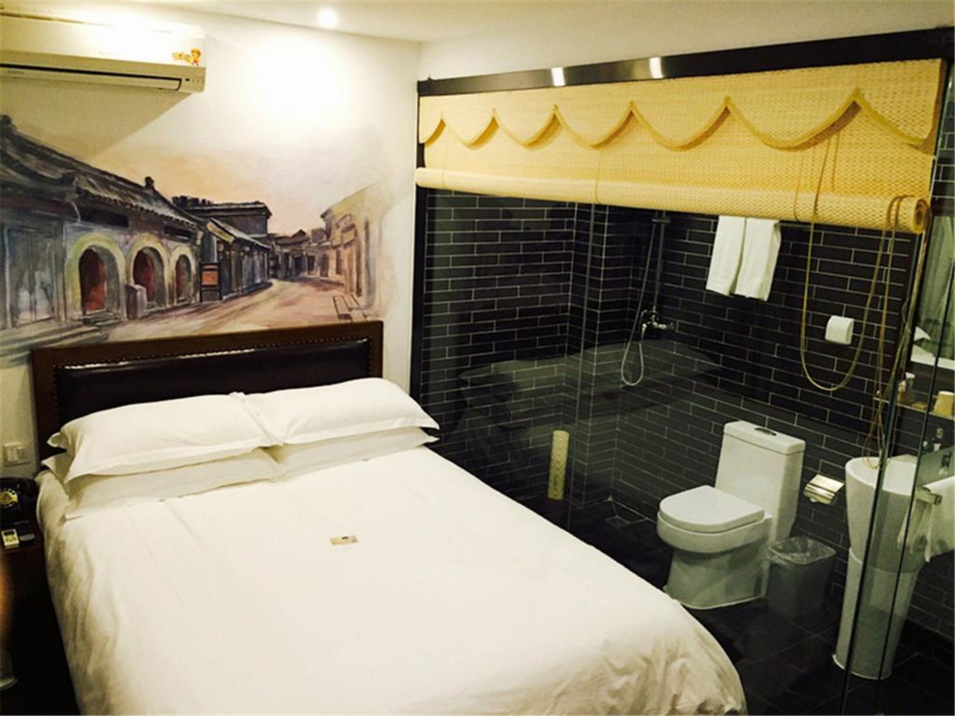 A hotel room with a bed, a shower area with a glass door, and a toilet.