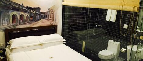 A hotel room with a bed, a shower area with a glass door, and a toilet.