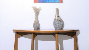 A wooden table with two vases and a painting on the wall above it. - Venetian Hotel (Addis Ababa)