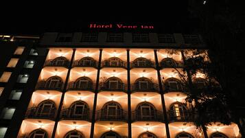 Un hôtel à plusieurs étages, doté de balcons et de fenêtres illuminées la nuit.