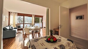 En matplats med ett bord för fyra personer, en soffa och utsikt över omgivningarna.