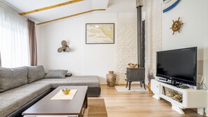 Un salon moderne comprenant un canapé, une table basse, un téléviseur, une cheminée et un élément décoratif mural.