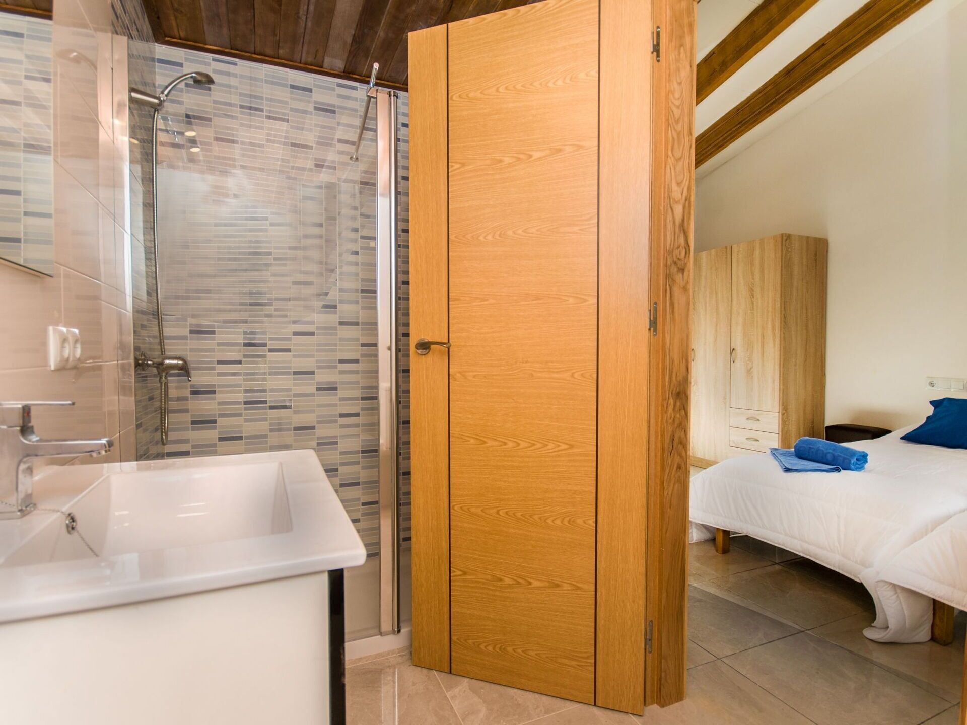 Une salle de bain avec douche, lavabo et armoire en bois.