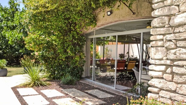A covered patio with stone walls, a glass enclosure, and outdoor furniture.