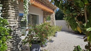 A stone building with a tiled roof, potted plants, and a gravel driveway.