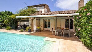 A house with a swimming pool, a patio with outdoor furniture, and a garden.