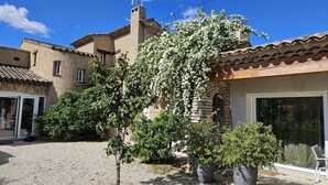 A residential building with a stone facade, a tiled roof, and a gravel driveway.