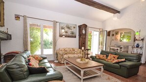 A spacious living room with two green sofas, a wooden coffee table, and a large window providing natural light.