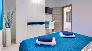 A modern bedroom with a bed, a wardrobe, a desk, and a TV.
