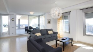 En moderne stue med en grå modulsofa, et sofabord og et spiseområde med bord og stole.