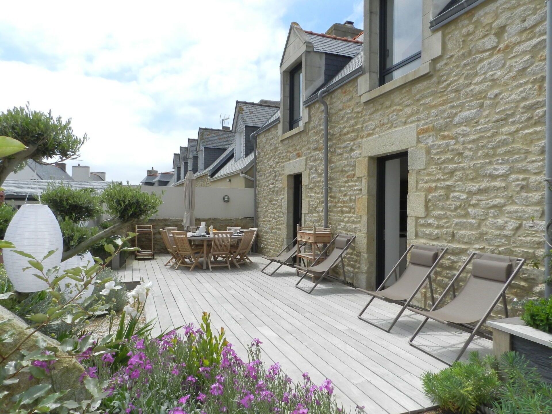 A courtyard with a wooden deck, outdoor seating, and stone walls.