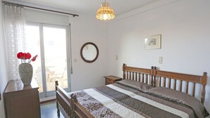 A bedroom with a wooden bed, a bedside table, a mirror, and a vase with flowers. - Cosy apartment for 6 guests with WIFI, A/C, TV, terrace and pets allowed (L'ampolla)
