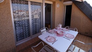 A dining area with a table set for four, featuring pink and white tableware, and metal chairs. - Cosy apartment for 6 guests with WIFI, A/C, TV, terrace and pets allowed (L'ampolla)