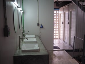 A bathroom with three sinks, a mirror, and a door leading to another room. - Hybrit Hostel & Cafe (Hat Yai)