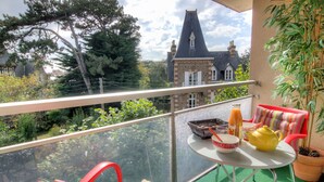 A balcony with a table, chairs, and a potted plant. - Cosy apartment for 2 guests with WIFI, TV, balcony and pets allowed (Dinard)