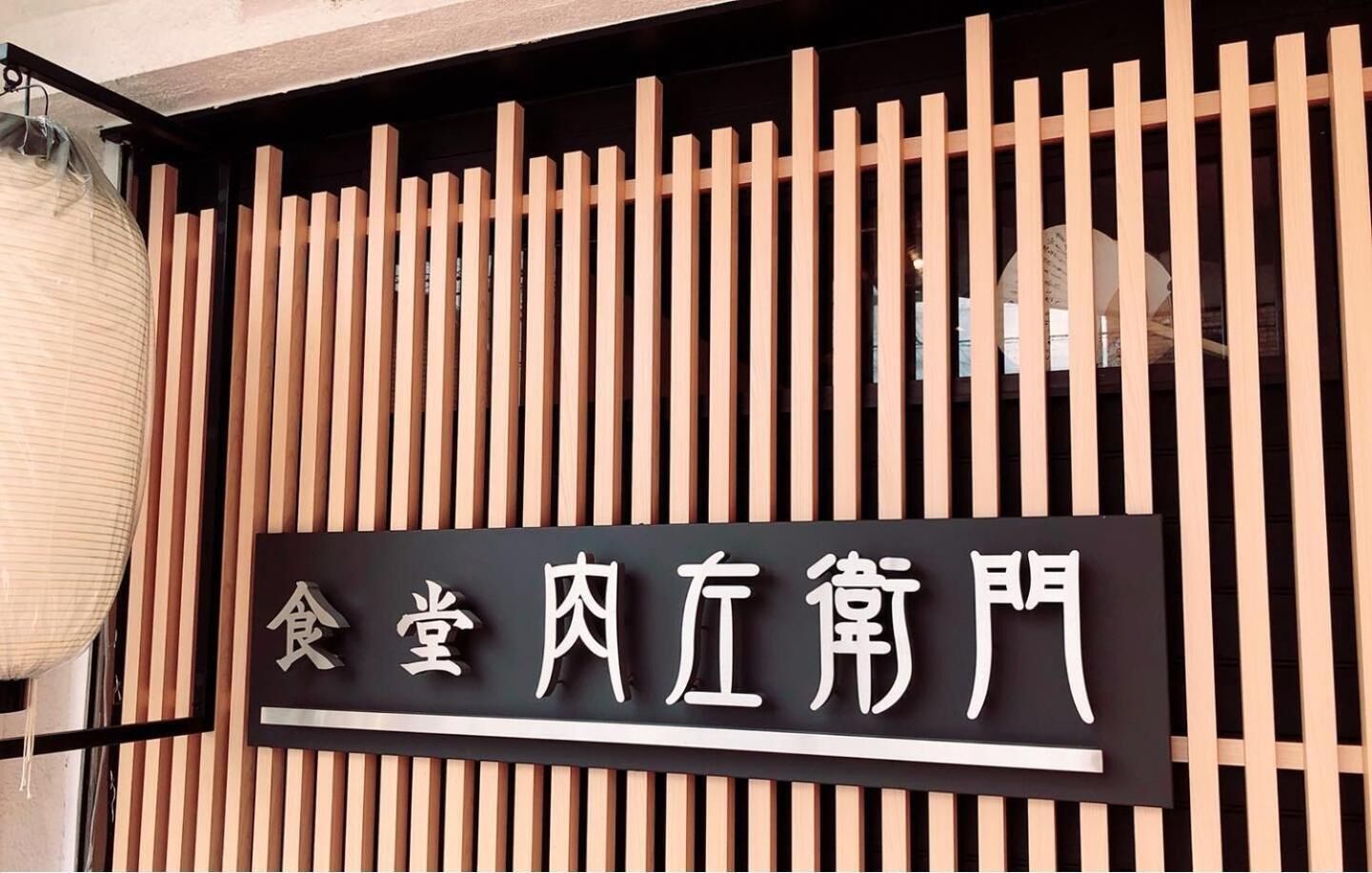 A sign with Chinese characters, mounted on a wooden slat wall.