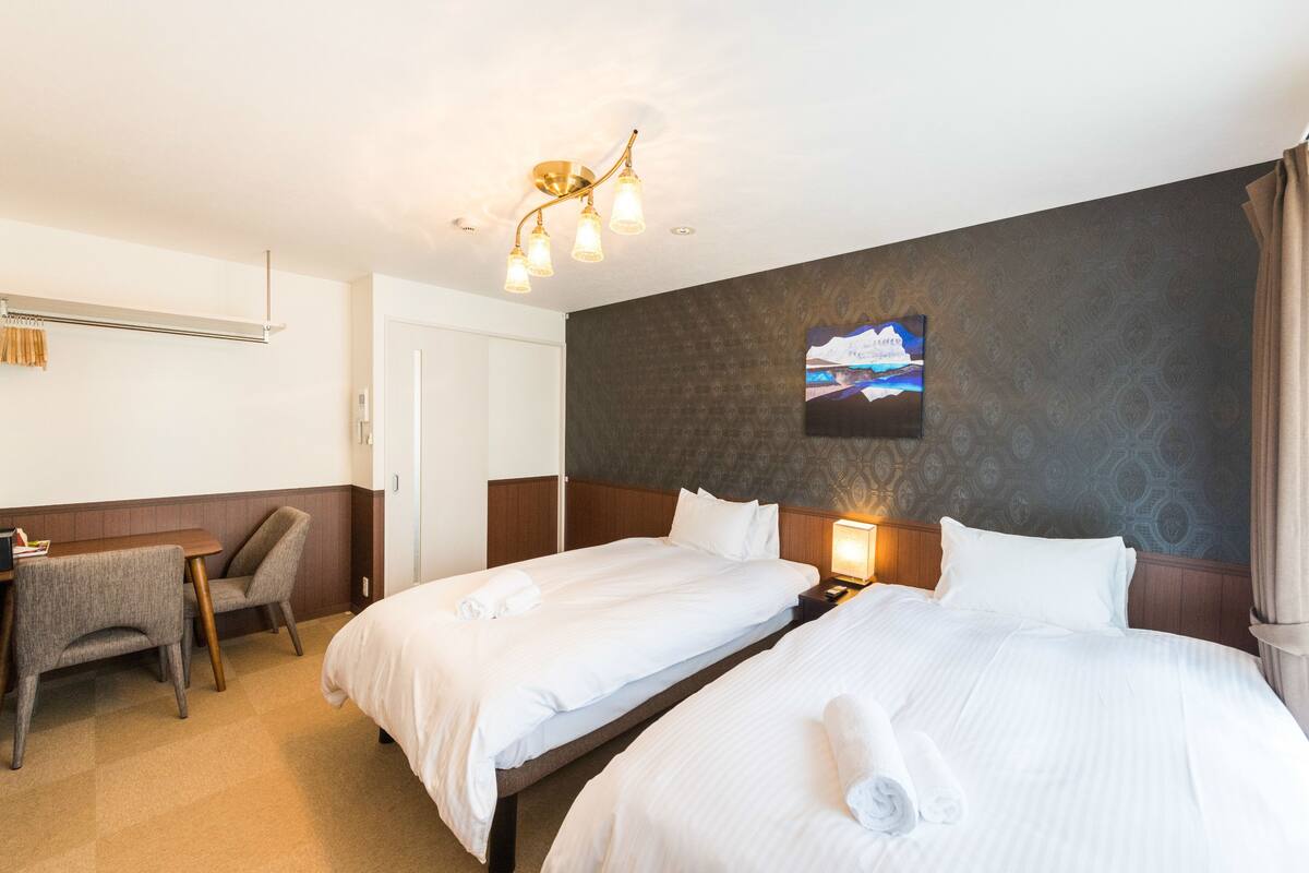 A hotel room with two beds, a desk, and a chair.