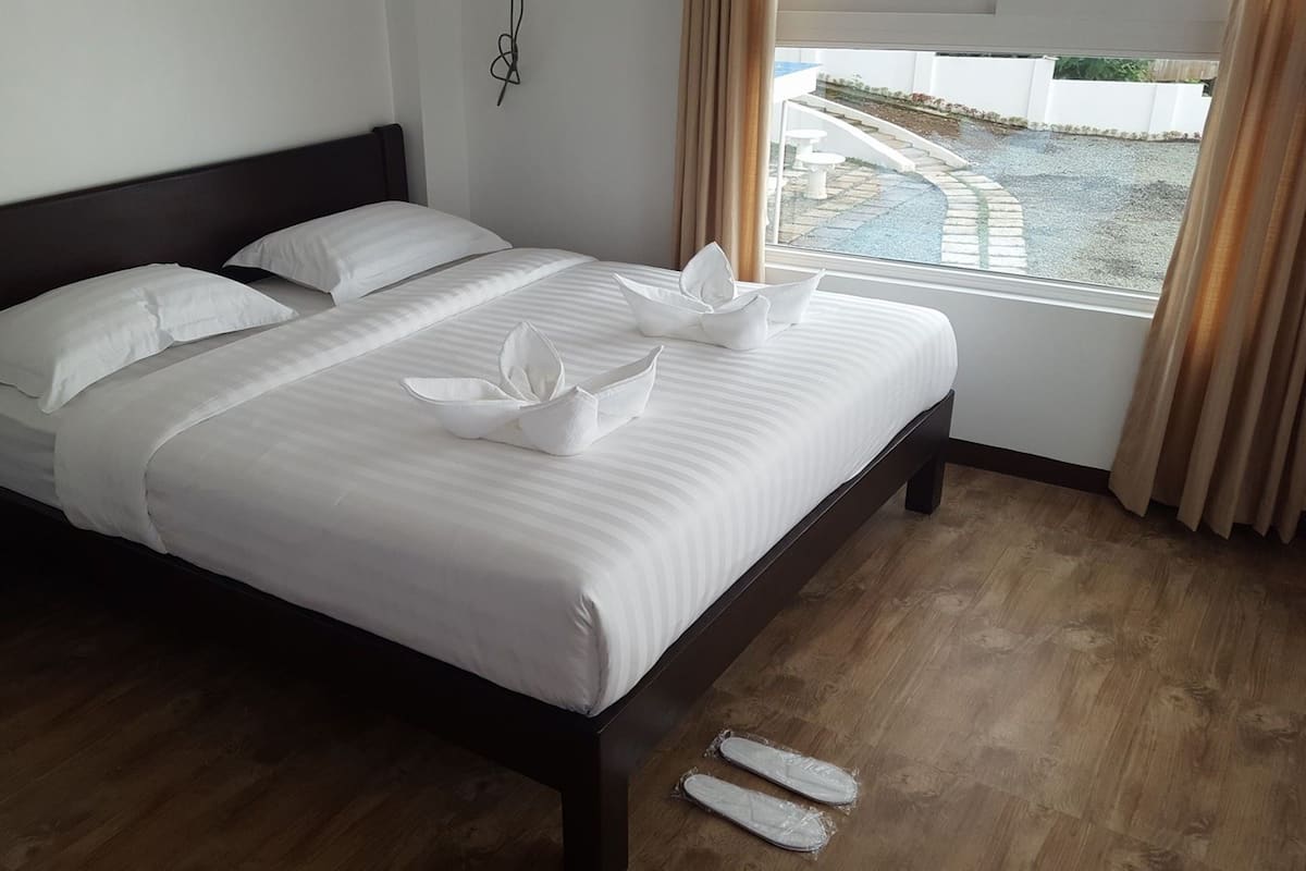 A neatly made bed with white linens and a decorative pillow arrangement.