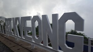 Uma placa grande e branca com a palavra 'RIKEONG' numa cerca de metal.