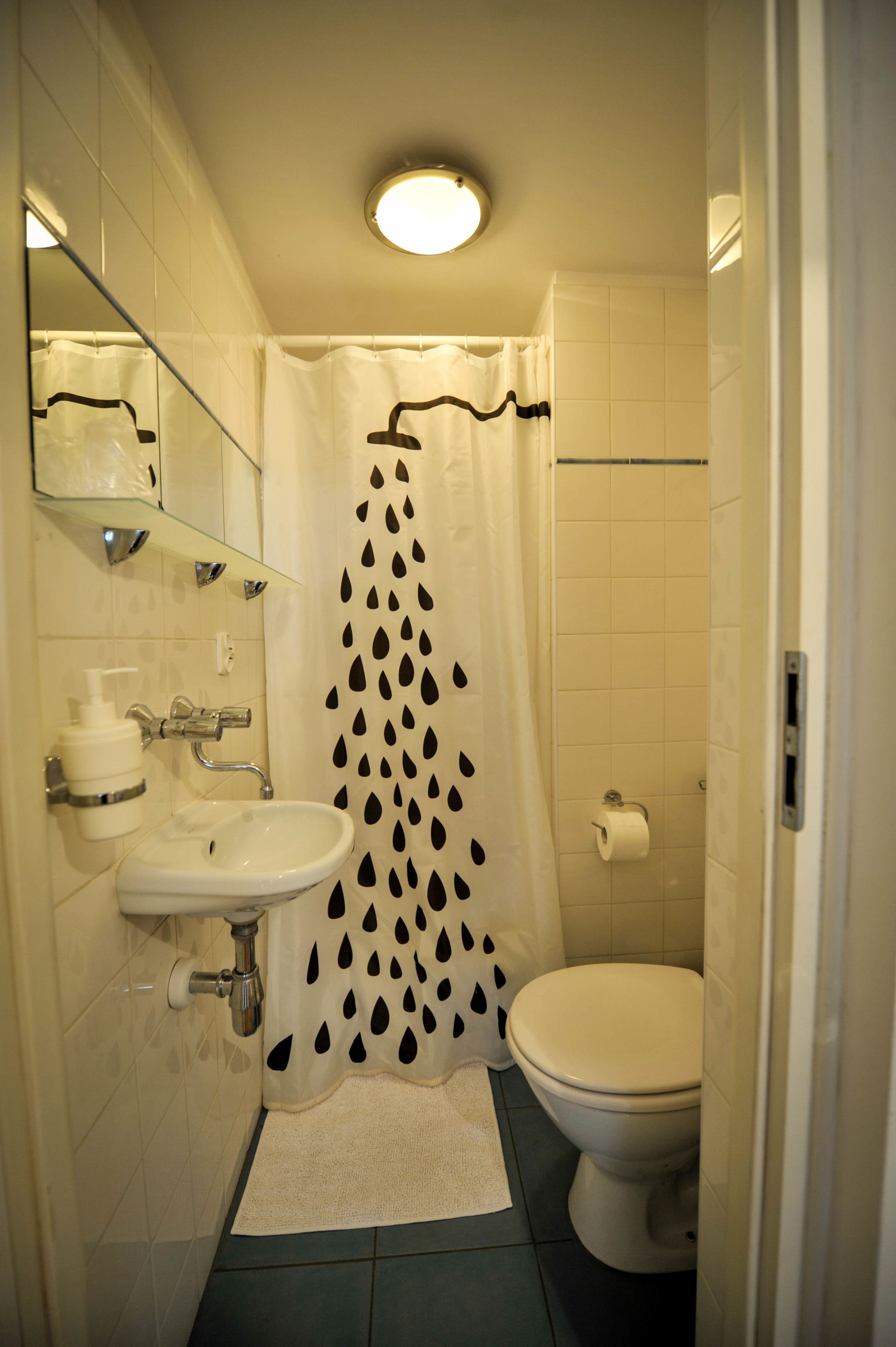 Kylpyhuone, jossa on pesuallas, wc ja suihkuverho.